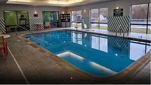 An indoor swimming pool with a lifeguard warning sign, chairs, and a view of the outside. - Holiday Inn Cheshire - Southington by IHG (Southington)