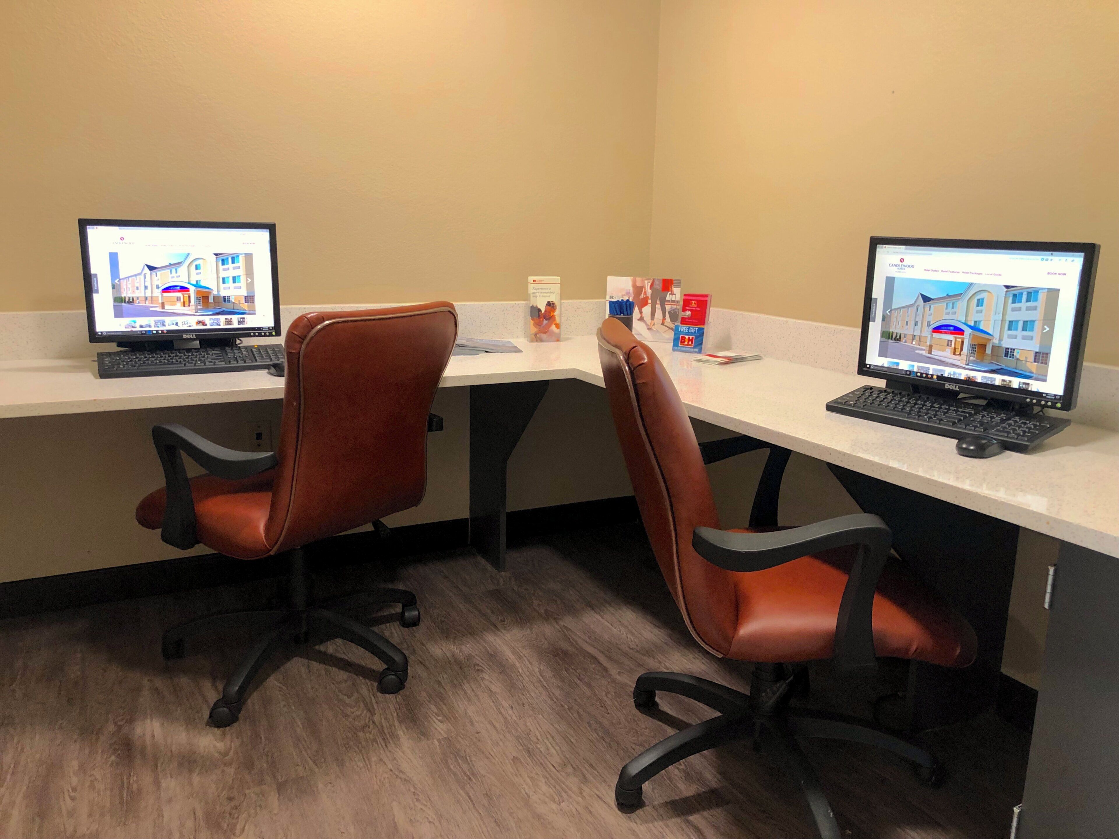 A workspace with two desks, each with a computer, two brown office chairs, and a white countertop.