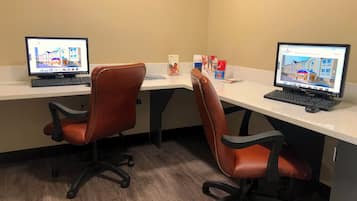 A workspace with two desks, each with a computer, two brown office chairs, and a white countertop.