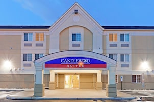 Entrada de un hotel con un letrero que dice 'CANDLEWOOD SUITES' y un cielo despejado arriba.