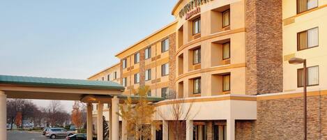 Hotel Courtyard by Marriott con estacionamiento techado, varios pisos y fachada de piedra.