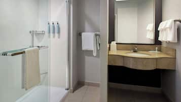 A modern bathroom with a glass shower enclosure, a vanity with a granite countertop, and a mirror above the sink.