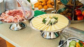 Un buffet proposant une variété de plats, notamment des viandes, des fromages, des fruits et des légumes.