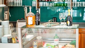 Une présentation variée de produits alimentaires et de boissons, comprenant une sélection de fromages, de charcuteries et une bouteille d’huile d’olive Bertolli.
