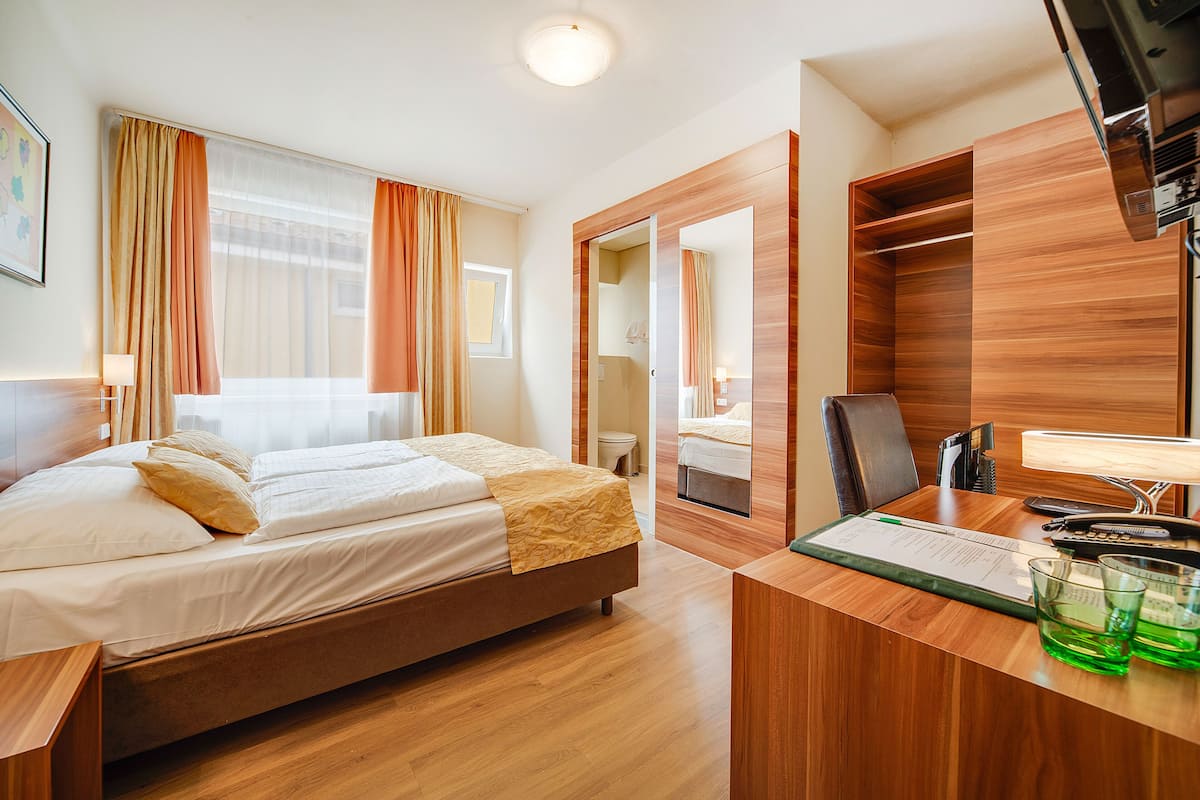 Een hotelkamer met een bed, een bureau met een computer en een kledingkast.