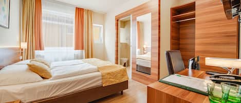 Una habitación de hotel con cama, escritorio con computadora y armario.