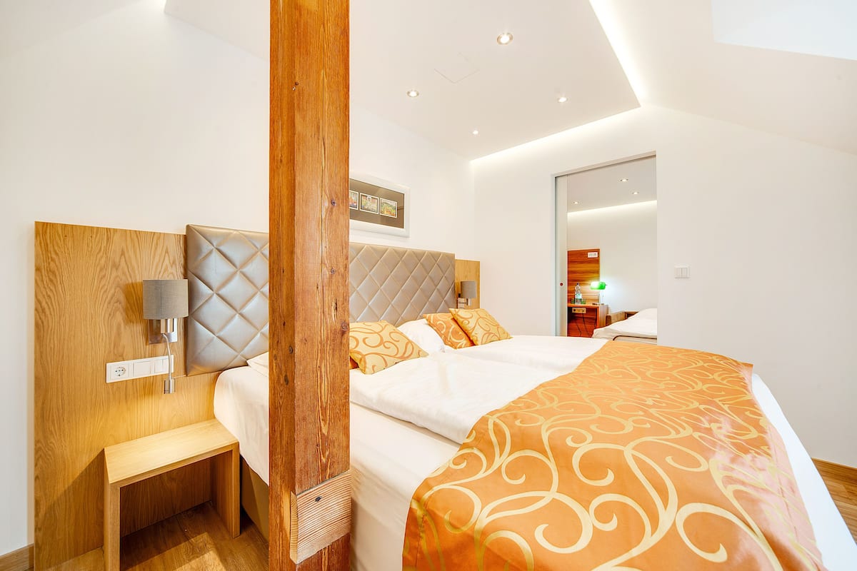 Een moderne slaapkamer met een houten hoofdbord, een nachtkastje, een bed met een bedovertrek met dessin en een wandlamp.