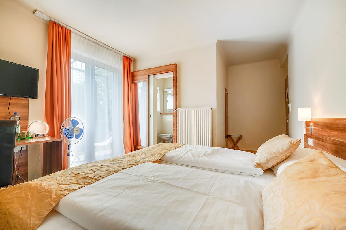 Een hotelkamer met een bed, een bureau met een computer, een televisie en een raam met gordijnen.
