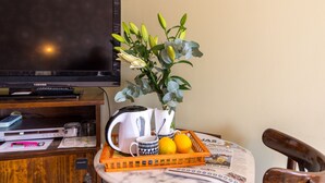 A television, a coffee maker, a tray with mugs and lemons, and a plant on a table. - Hostel El Escudo de Mijas (Mijas)