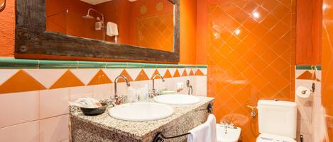 A bathroom with two sinks, a toilet, and a shower.