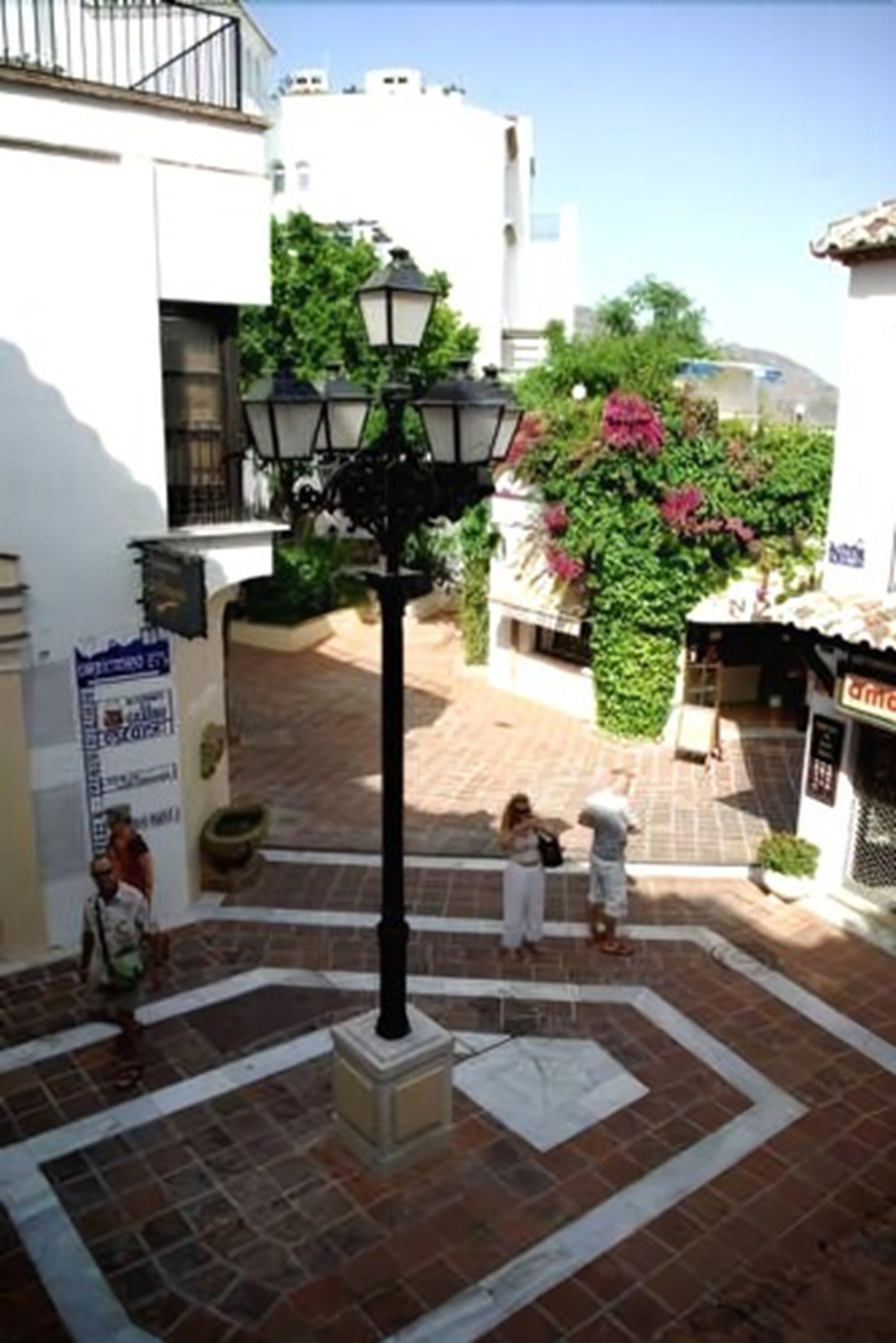 Une cour avec un sol carrelé, un lampadaire et un bâtiment portant une enseigne.