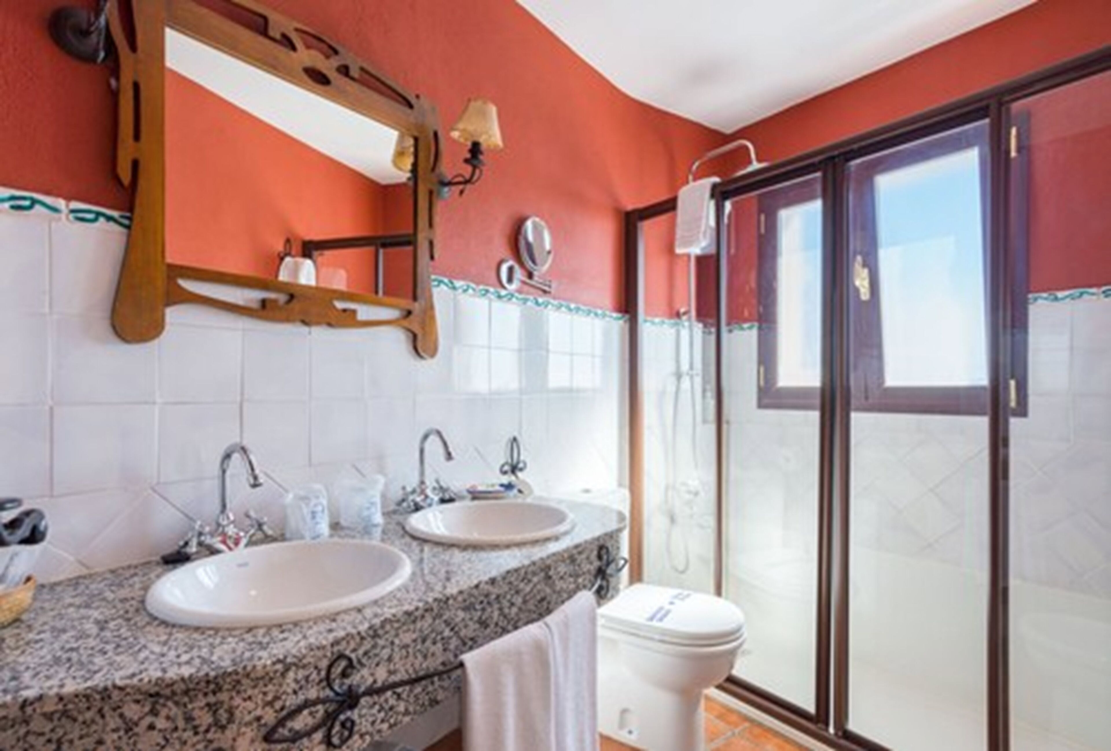 Une salle de bain avec deux lavabos, un miroir et une douche.