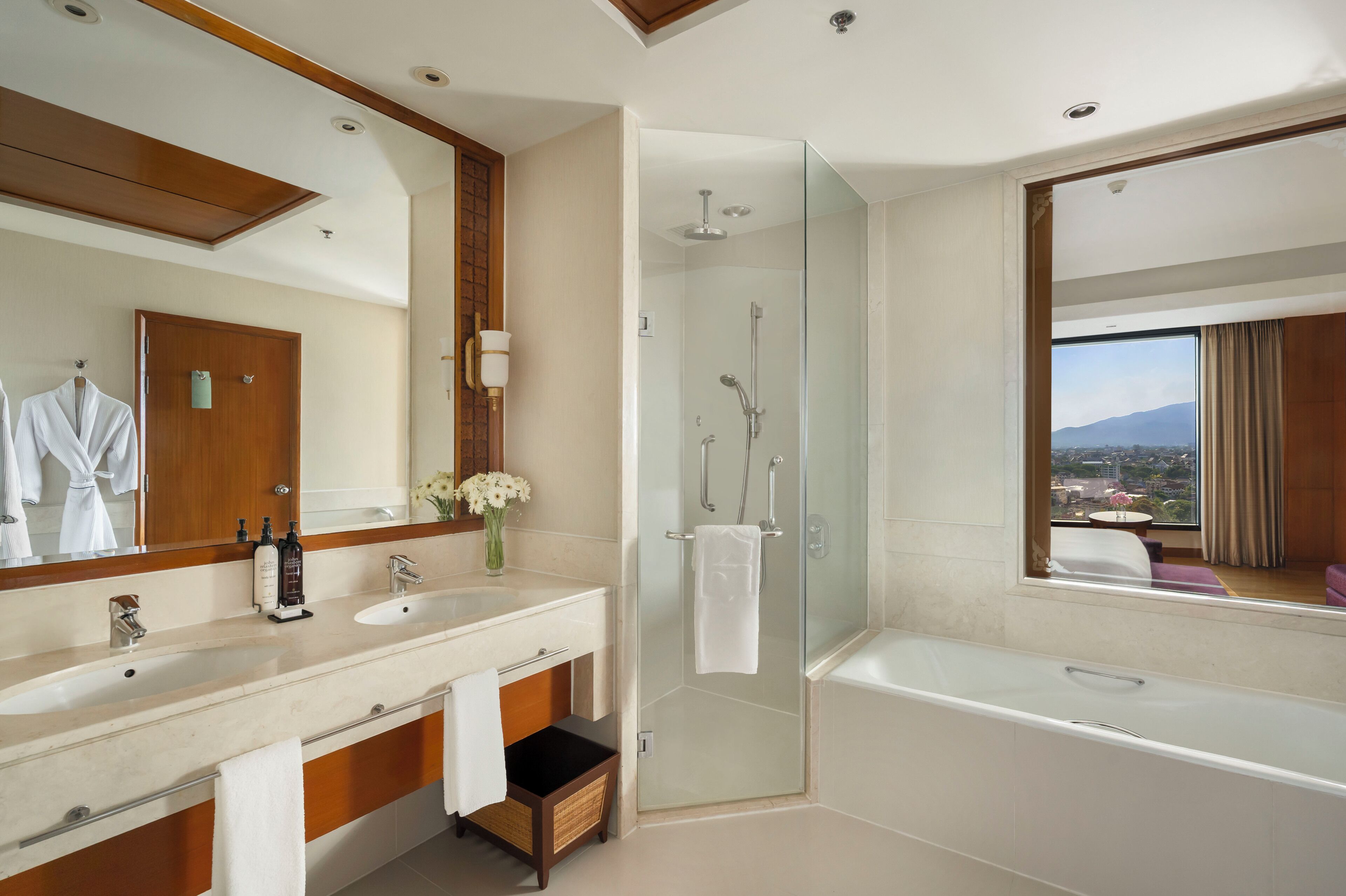 A modern bathroom with a large mirror, a bathtub, a shower, and a vanity with a sink and towel rack.