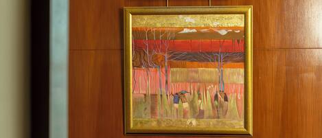A framed painting with a landscape scene on a wooden wall.