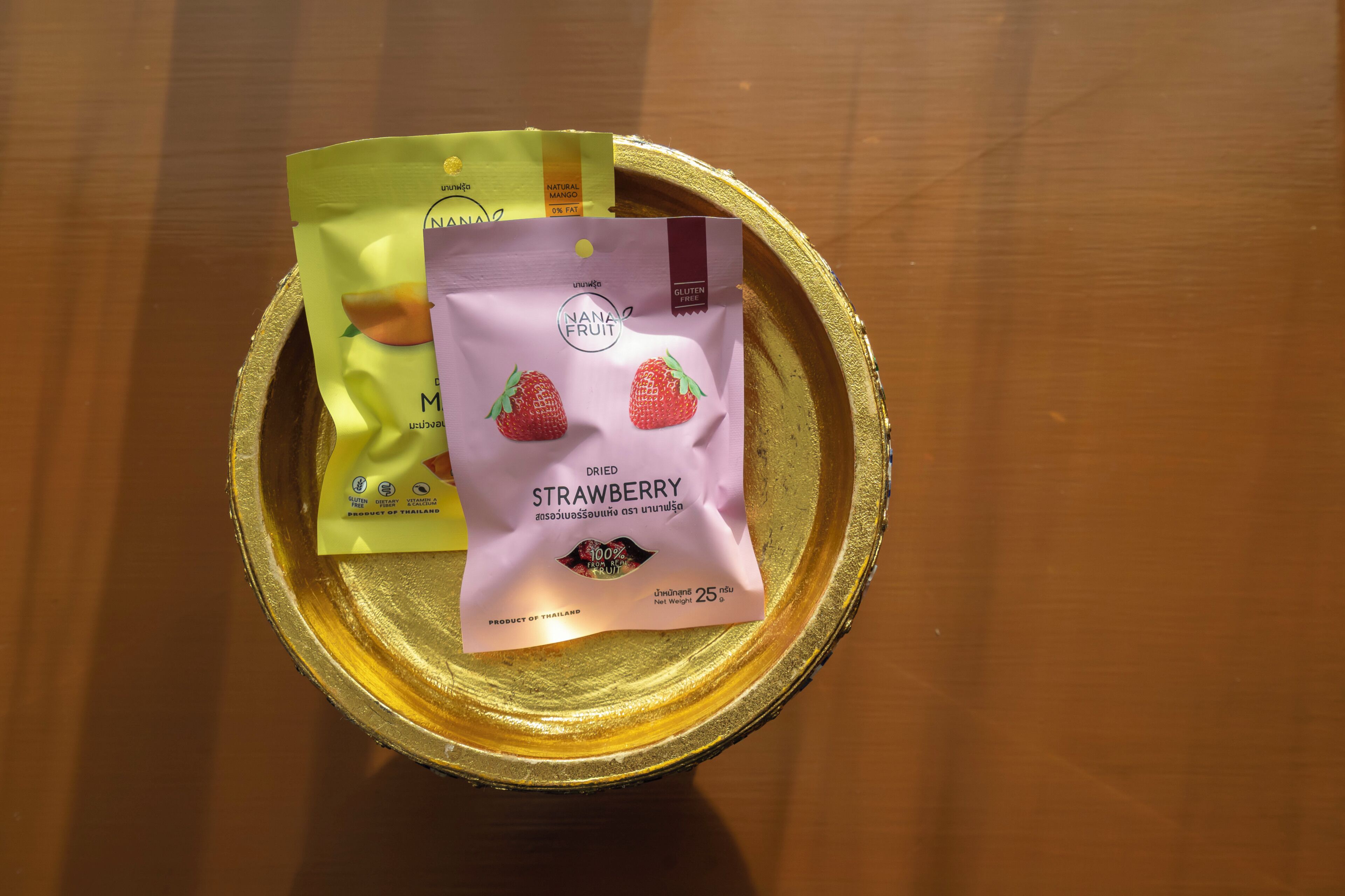 Un plateau contenant deux sachets de fruits secs, l’un portant la mention « FRUITS NANA » et l’autre « FRAISES NANA ».