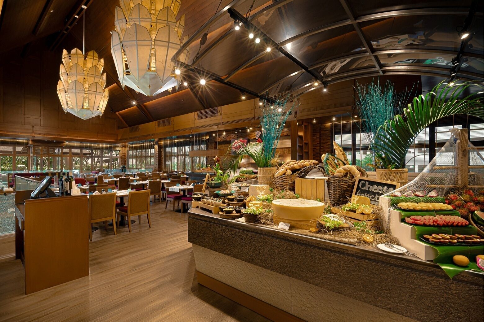 A restaurant with a buffet counter, wooden flooring, and hanging light fixtures.