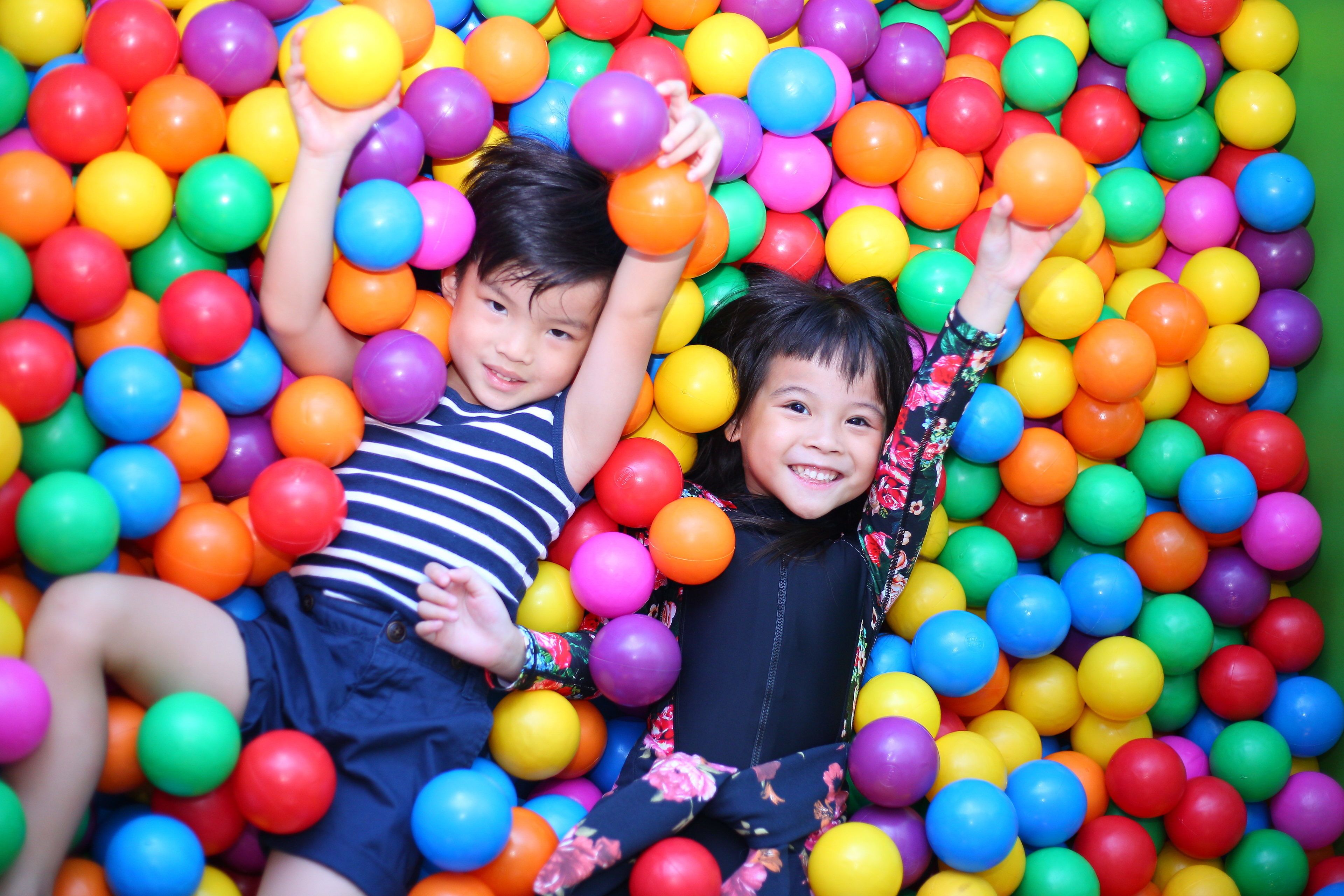 Two children playing in a ball pit filled with colorful balls.