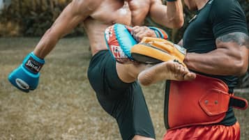 A person kicking a training dummy with a focus on the leg and foot.
