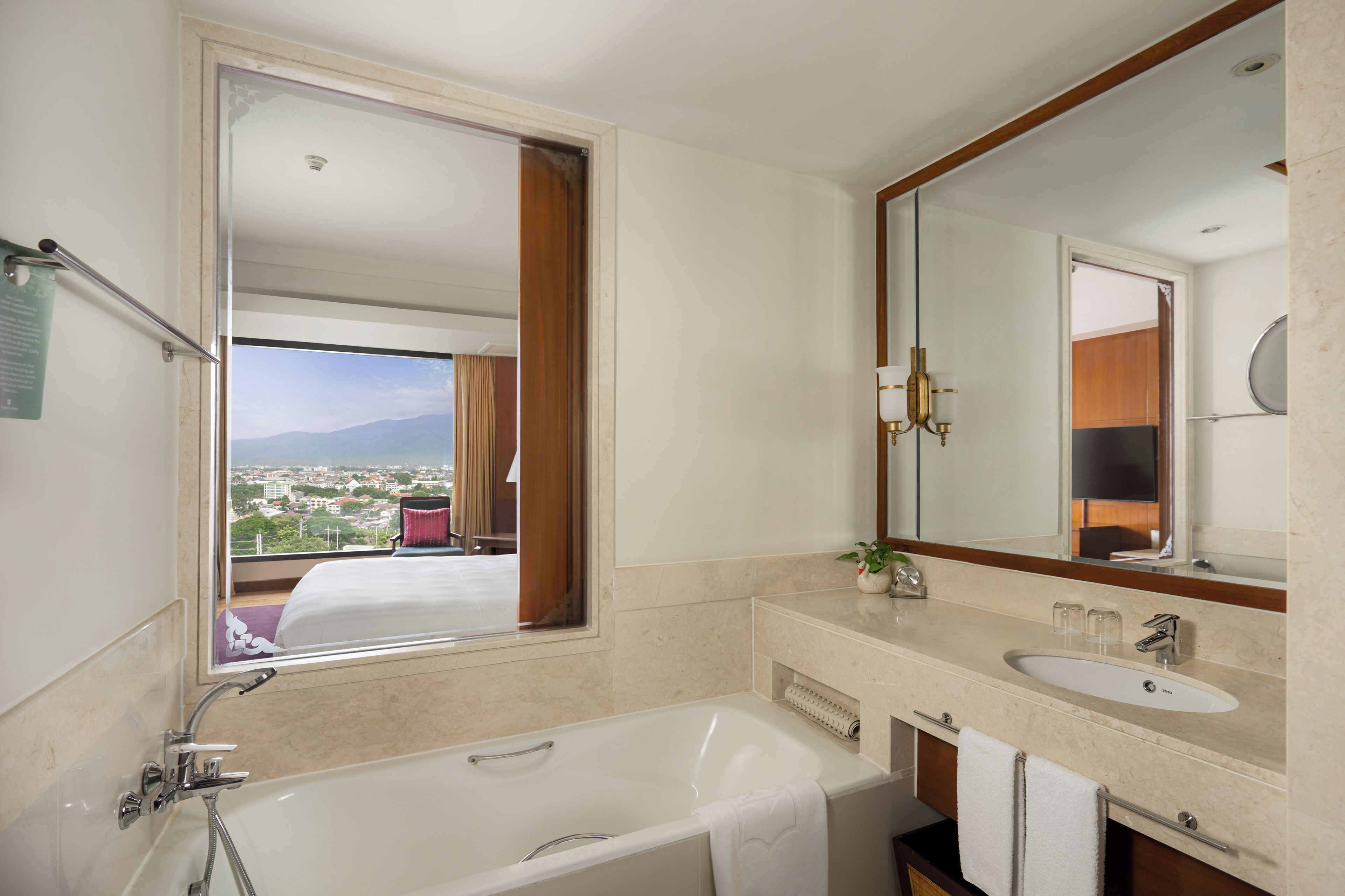 Un baño de hotel con bañera, lavabo y un espejo grande.