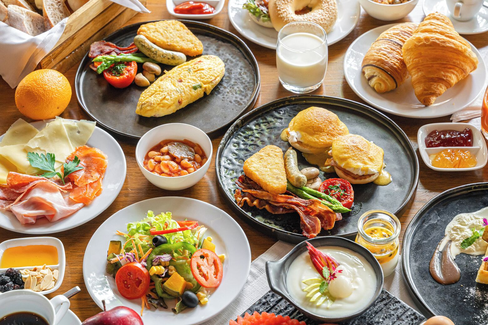Un bufé de desayuno con diversos platos, como huevos, tocino y pasteles.