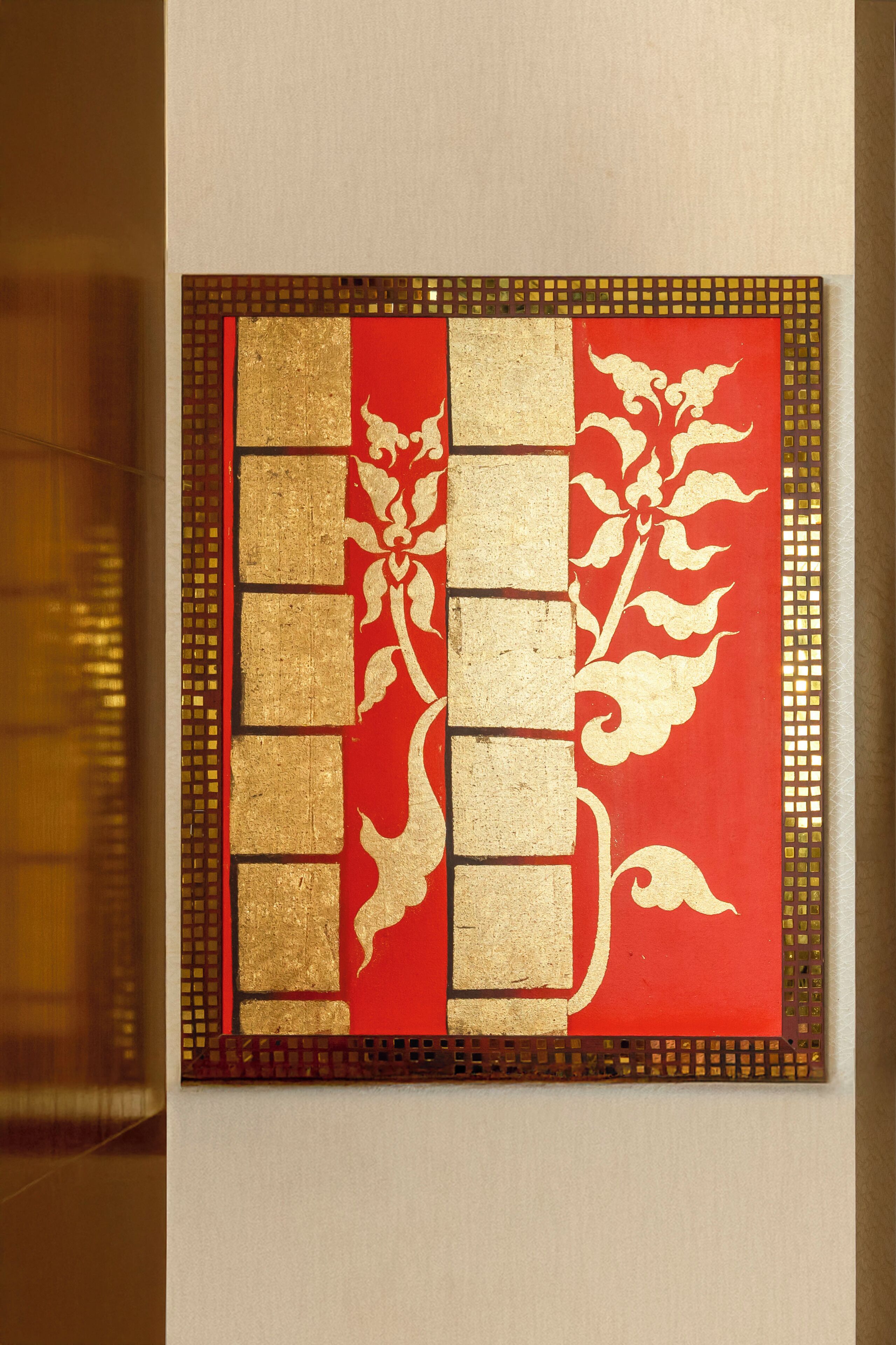 Una pared con un panel decorativo de diseño rojo y dorado.