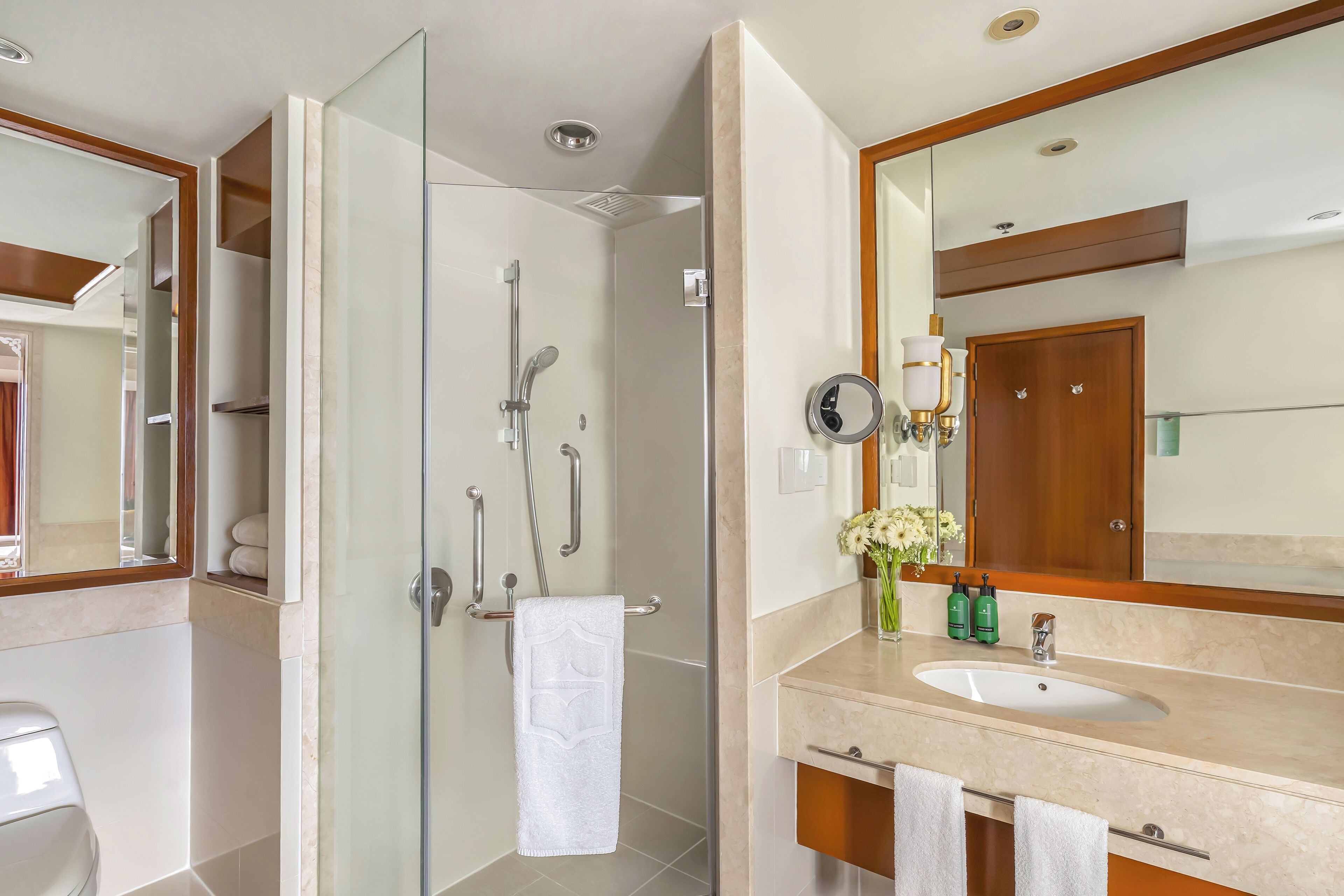 A modern bathroom with a glass-enclosed shower, a vanity with a sink, and a large mirror.