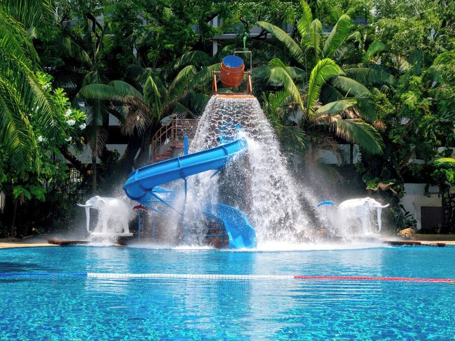 Eine Wasserrutsche über einem Pool, umgeben von üppiger Vegetation.