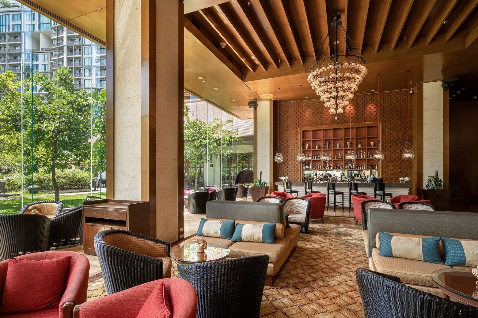 A modern lounge area with wicker furniture, a bar, and a view of greenery.