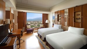 Une chambre d’hôtel avec deux lits, un bureau avec une télévision, une chaise, une vue sur la ville et un lambris en bois.