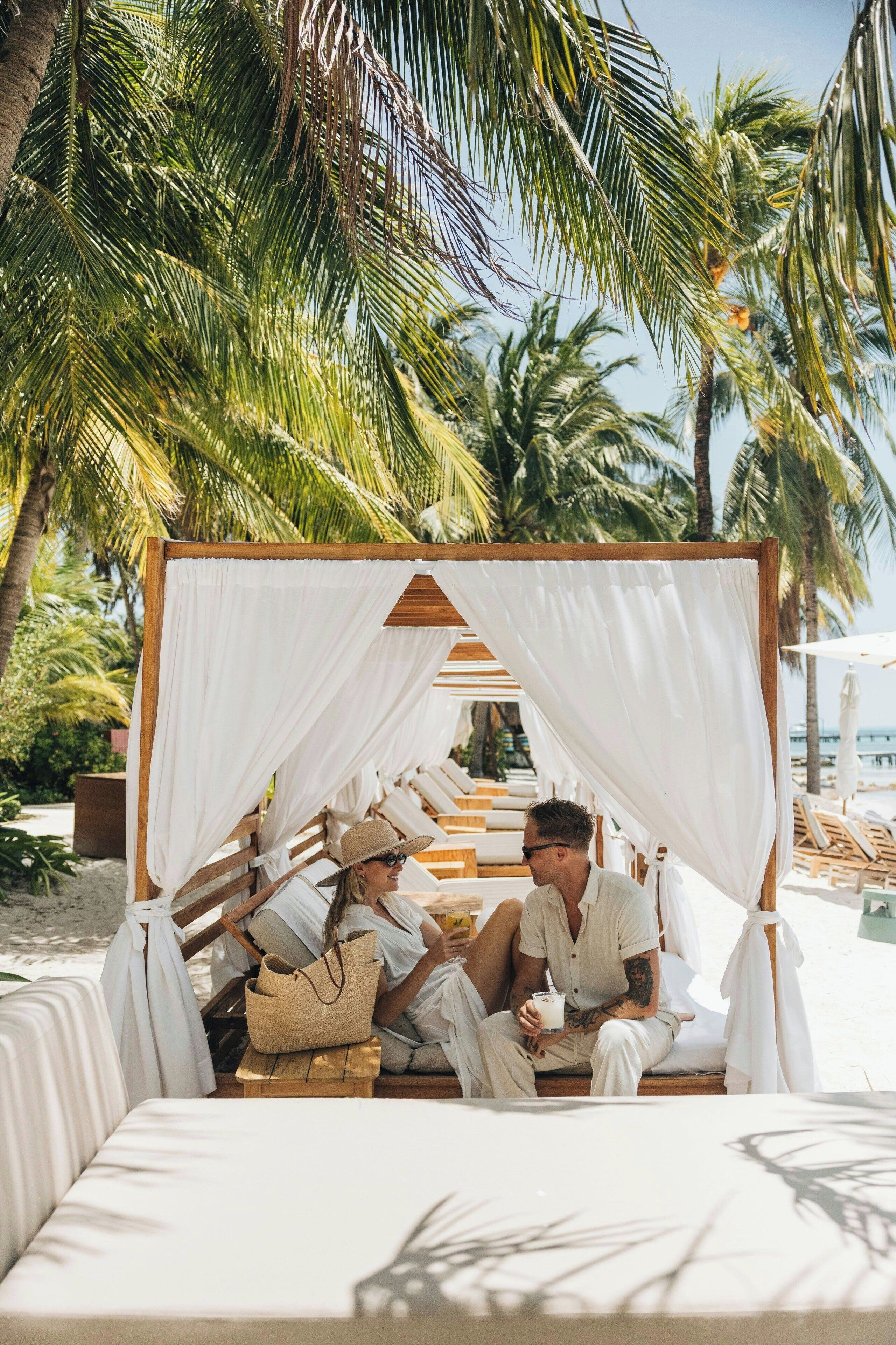 Di pantai, pasir putih, kerusi lepak pantai, payung 