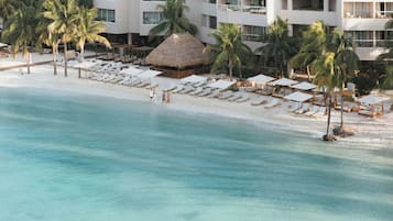 En la playa, arena blanca, sillas reclinables de playa, sombrillas