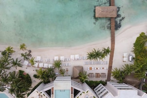 Vista aérea de un resort con playa, palmeras y zona de piscina.