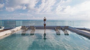 Un espace aménagé au bord de la piscine, avec des chaises longues et une vue sur la mer.