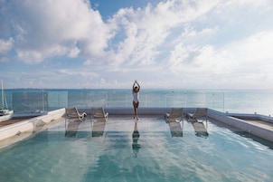 Zona de piscina con sillones de descanso y vista al mar.