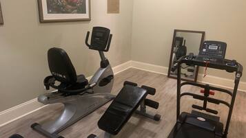 Ein Fitnessstudio mit Crosstrainer, Bank und Laufband.