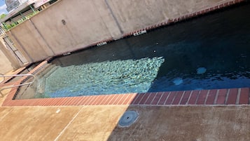 Una piscina al aire libre, sillones reclinables de piscina