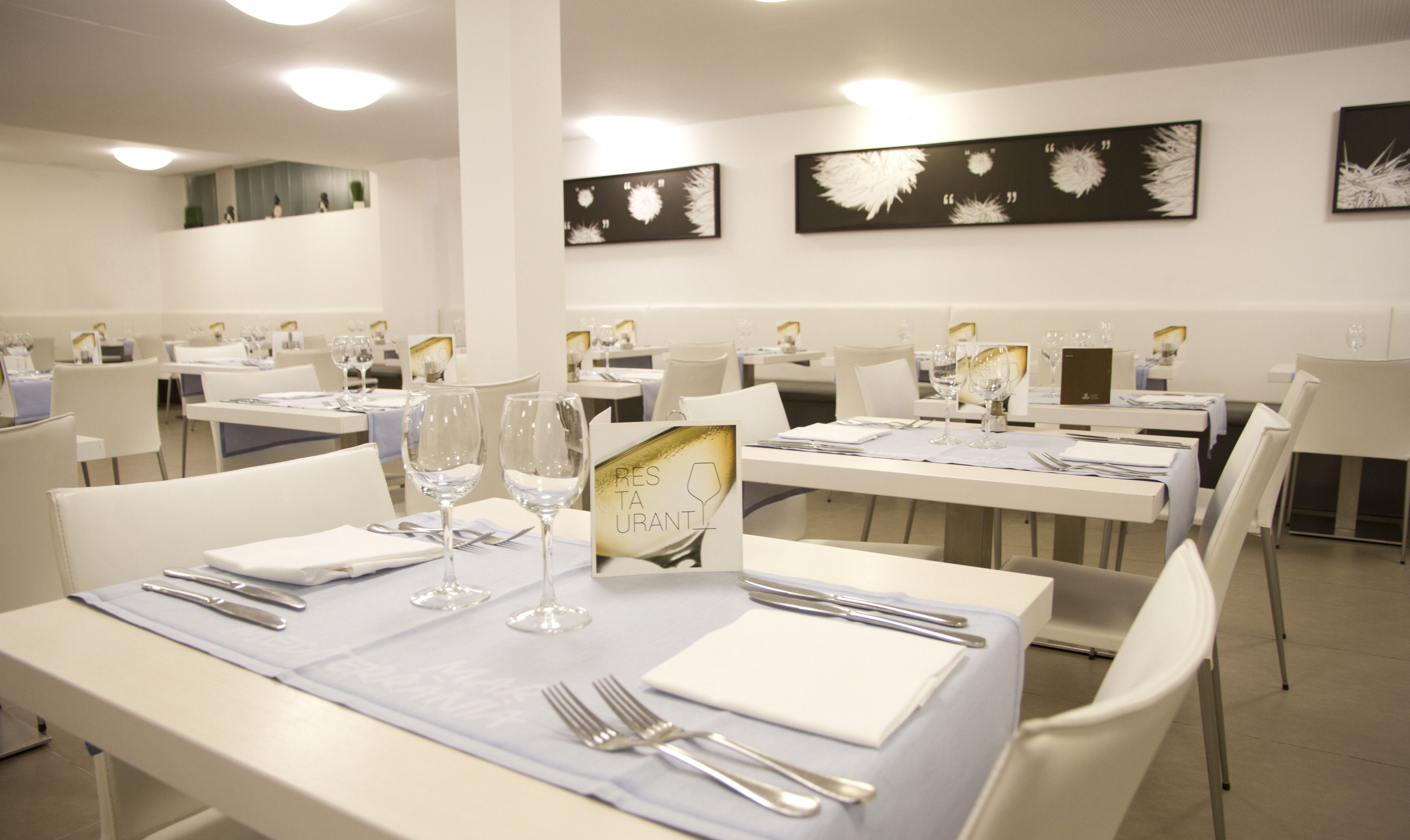 A restaurant with tables set for dining, featuring a menu stand and wine glasses.