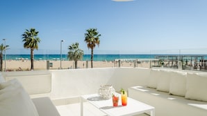 A balcony with a white sofa, a small table, and a view of the beach and ocean. - ALEGRIA Mar Mediterrania - Adults Only (Santa Susanna)