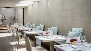 A modern dining area with tables set for four, each with white tablecloths, blue napkins, and clear glassware. - ALEGRIA Mar Mediterrania - Adults Only (Santa Susanna)