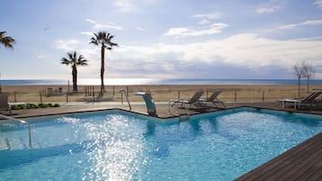 Una piscina techada, una piscina al aire libre, sombrillas