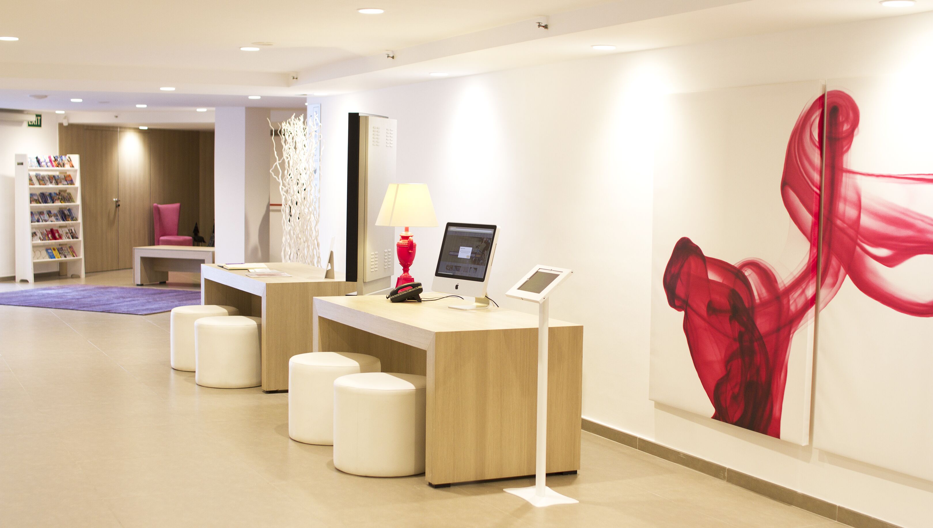 A reception area with a counter, a red lamp, and a large abstract painting.