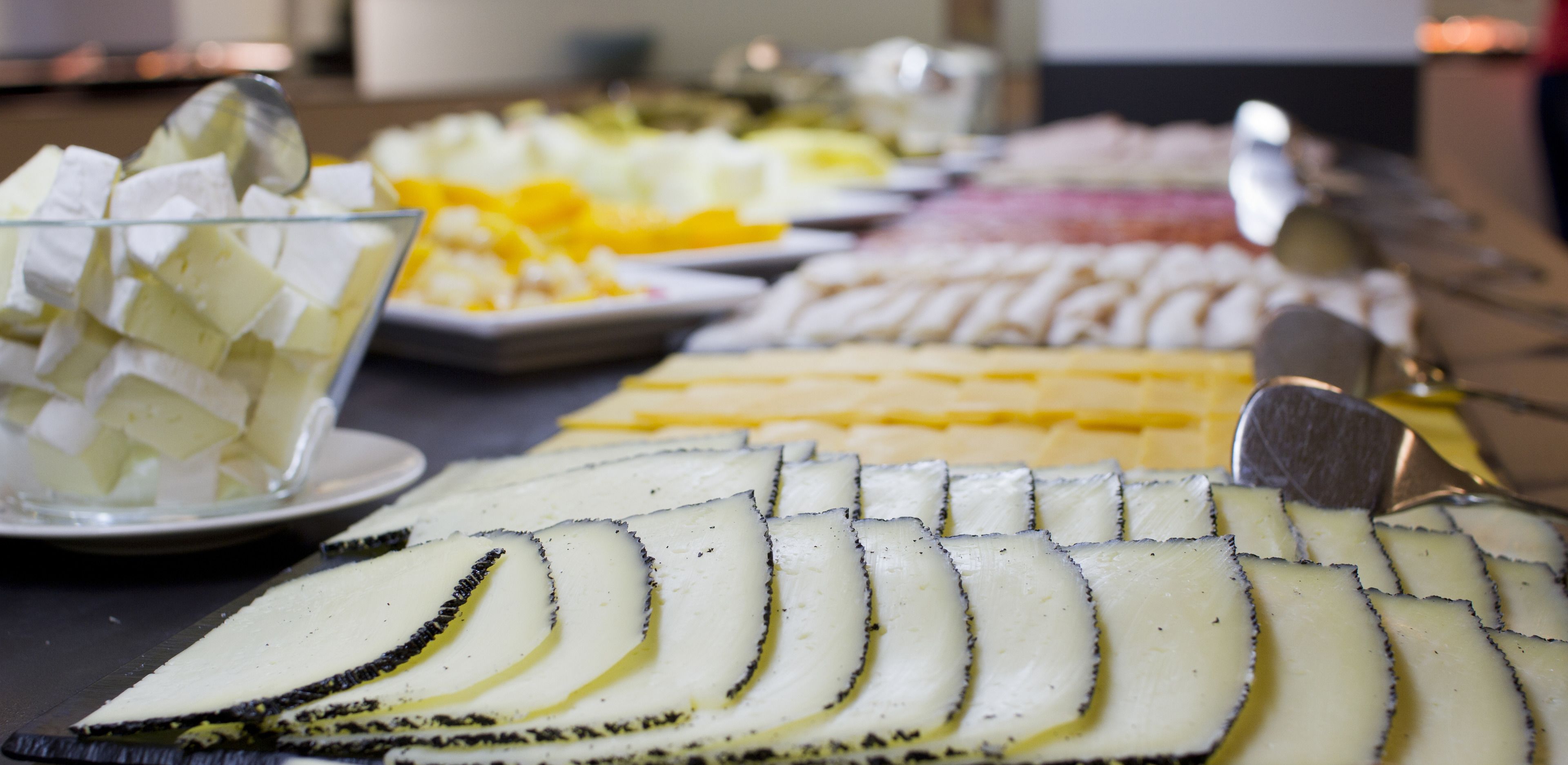 A buffet with various cheeses and fruits.