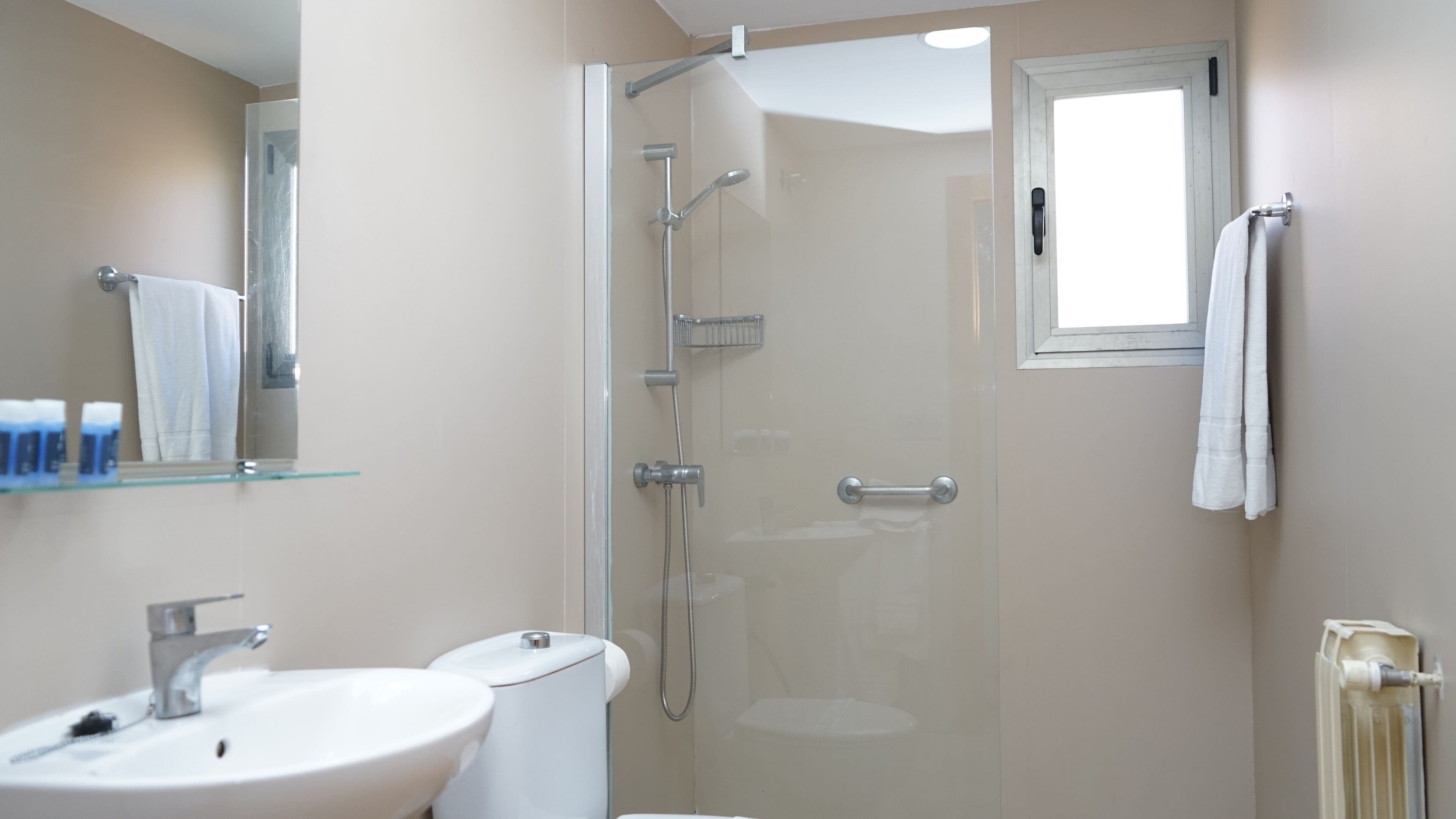 A modern bathroom with a glass-enclosed shower, a sink, and a toilet.