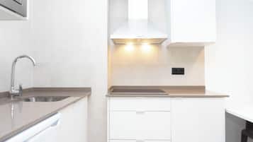 A modern kitchen with a stainless steel sink, white cabinetry, and a range hood.