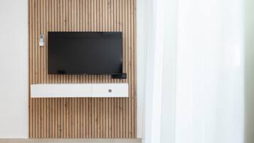 Una habitación moderna con un panel de madera en la pared, un televisor de pantalla plana montado y un mueble blanco debajo.