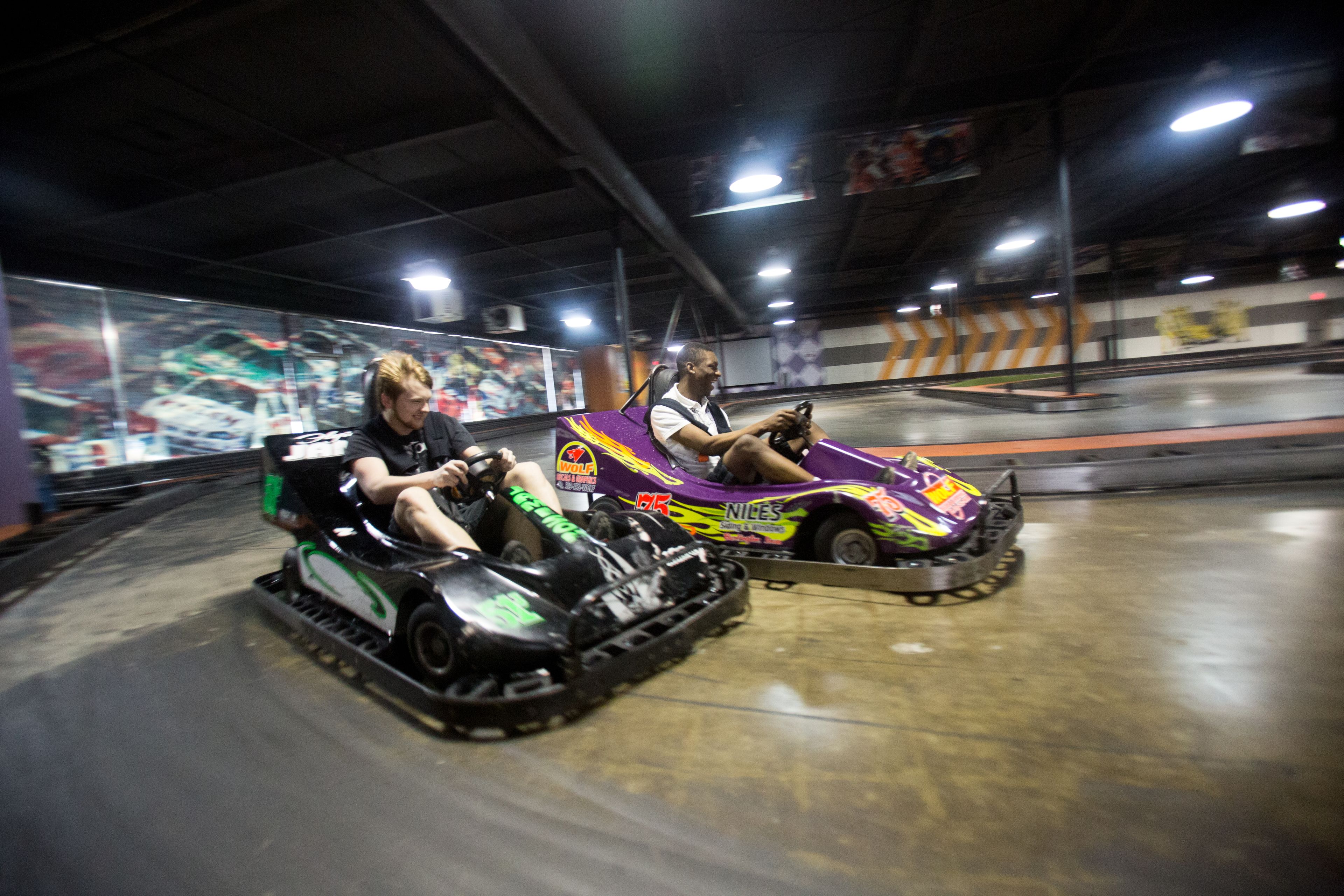 Two people in bumper cars at an indoor amusement park.