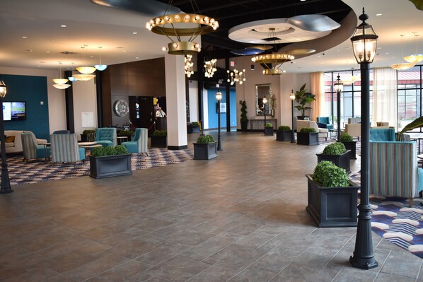 A spacious lobby with multiple seating areas, decorative lighting, and potted plants.