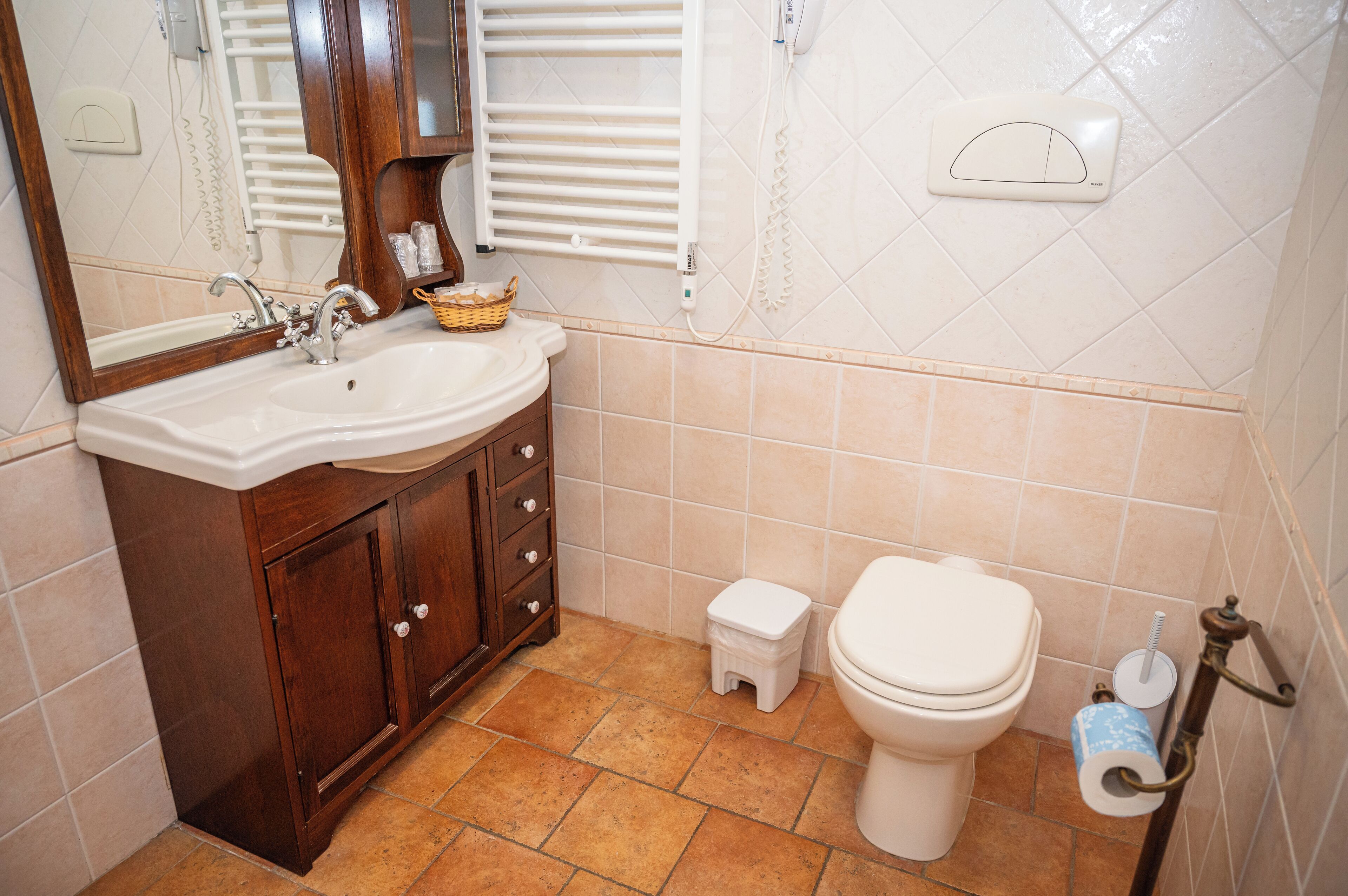 Un baño con lavamanos, espejo, armario, inodoro y un pequeño taburete.