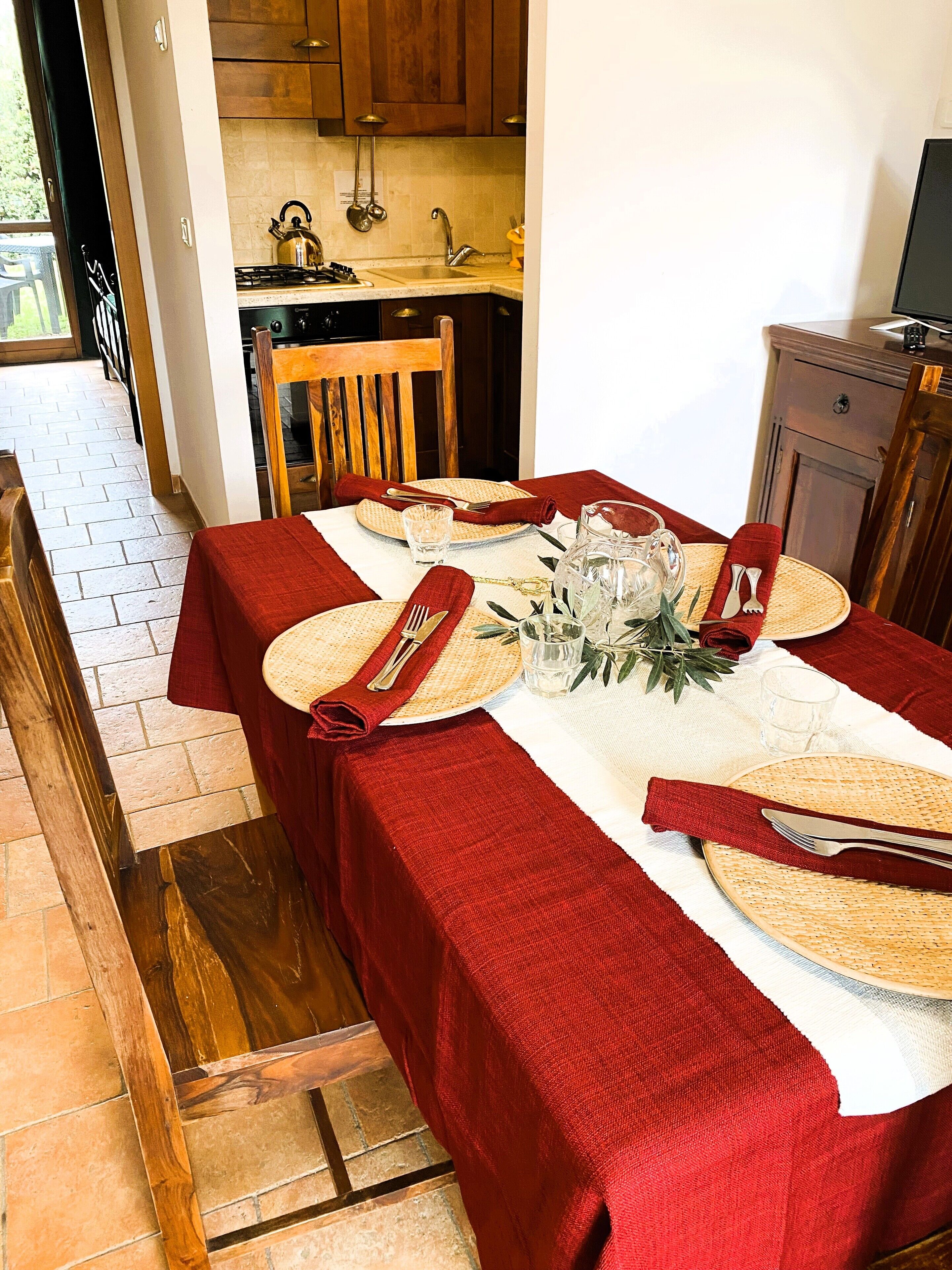 A dining table set with red tablecloths, woven placemats, and cutlery.