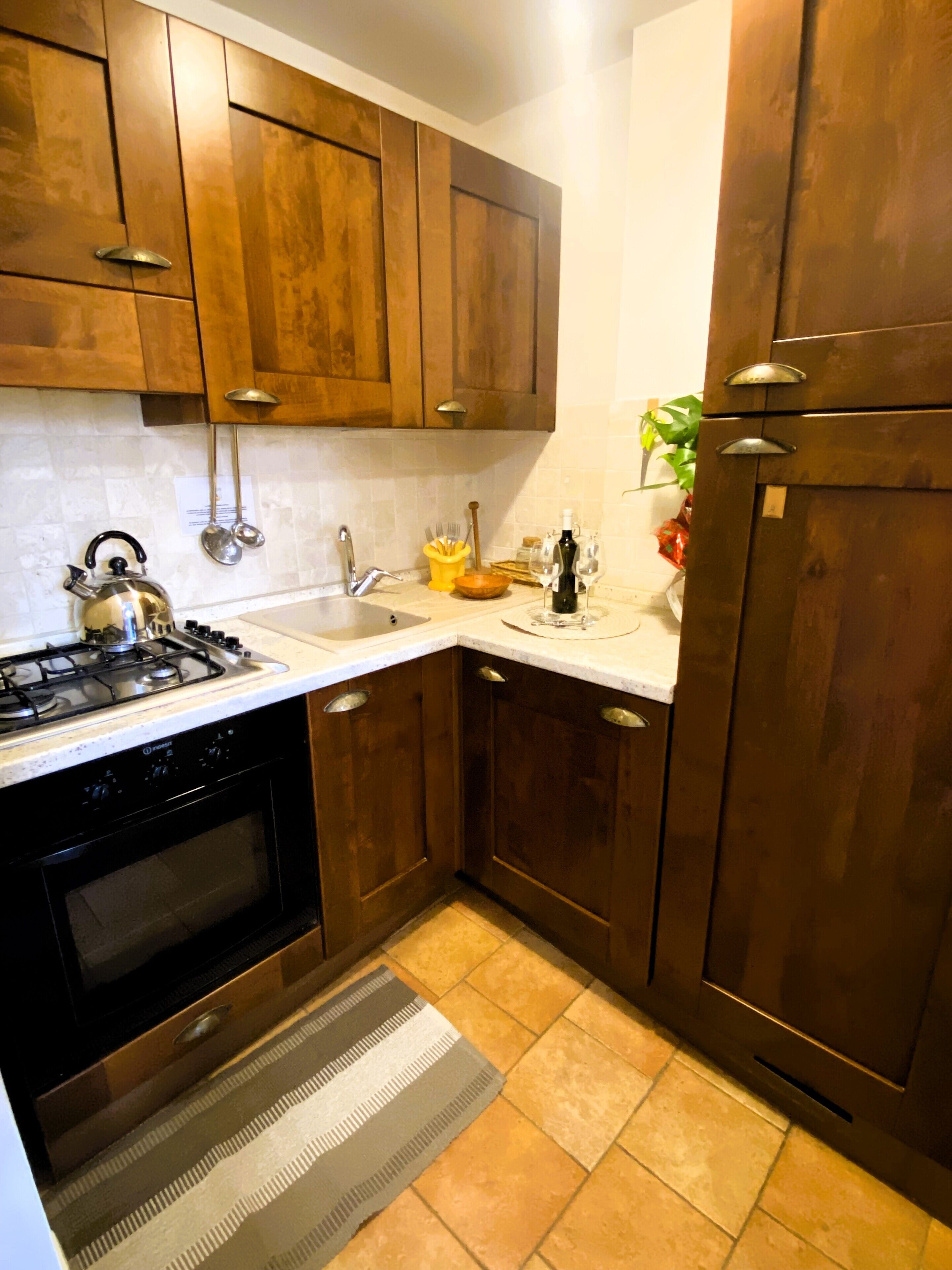 A kitchen with wooden cabinets, a gas stove, a sink, and a refrigerator.